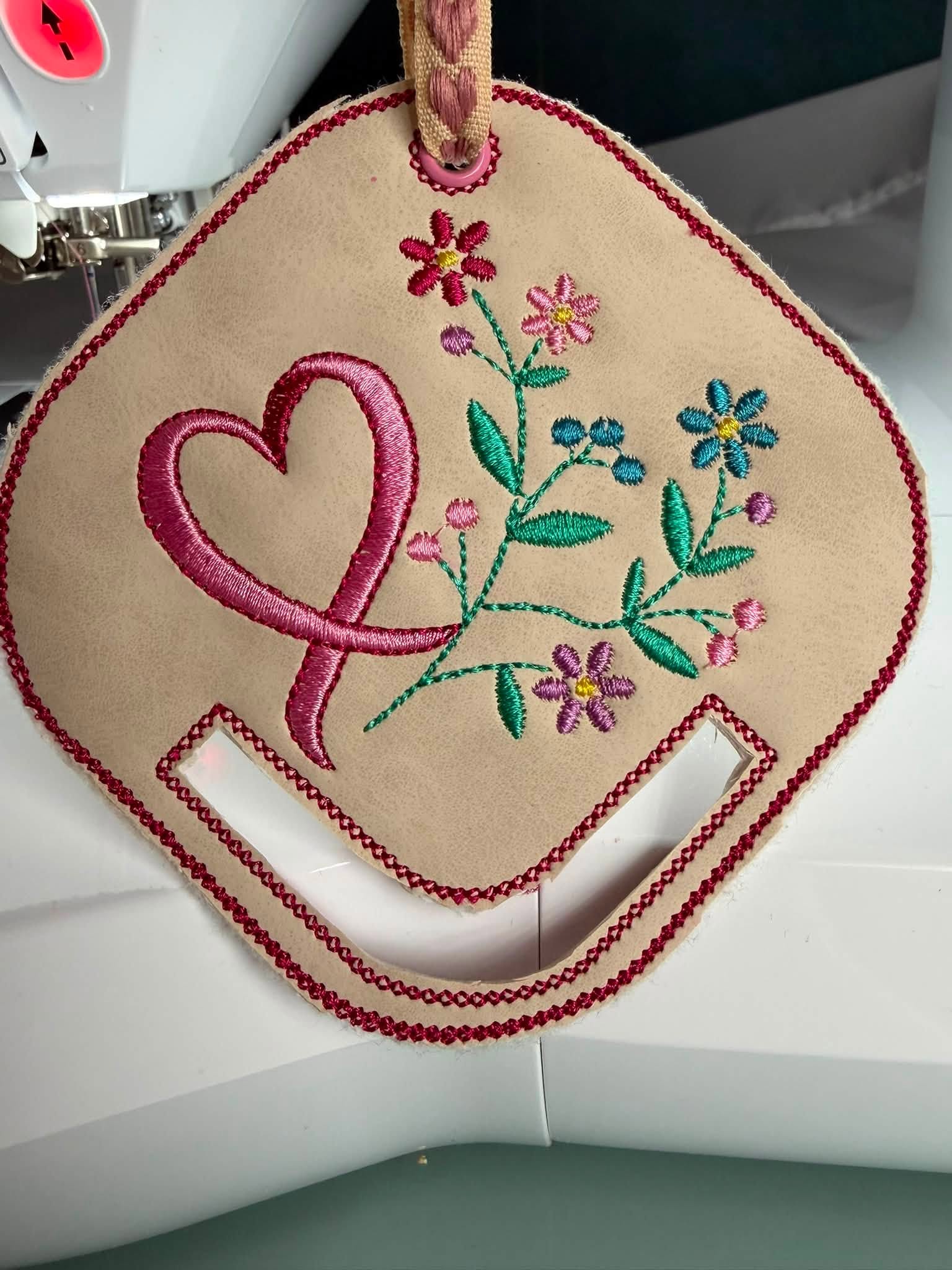 Motif de broderie ITH porte-foulard Ruban & Fleurs Octobre Rose avec ruban rose, fleurs délicates et feuillage, format 10x10