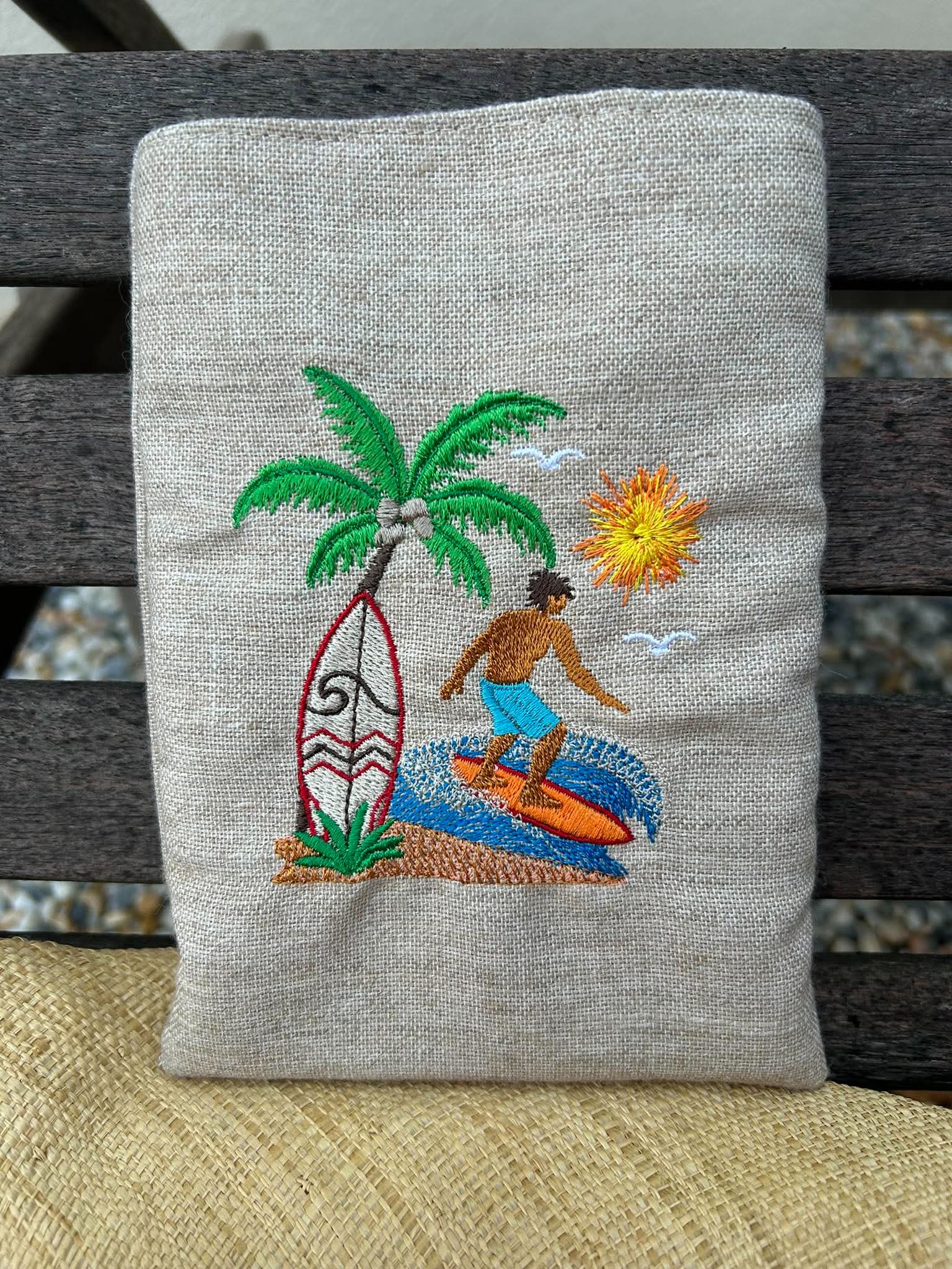 Motif de broderie Surfeur disponible au format 10x10. Décor tropical avec palmier, planche de surf, océan et soleil, idéal pour une ambiance estivale.