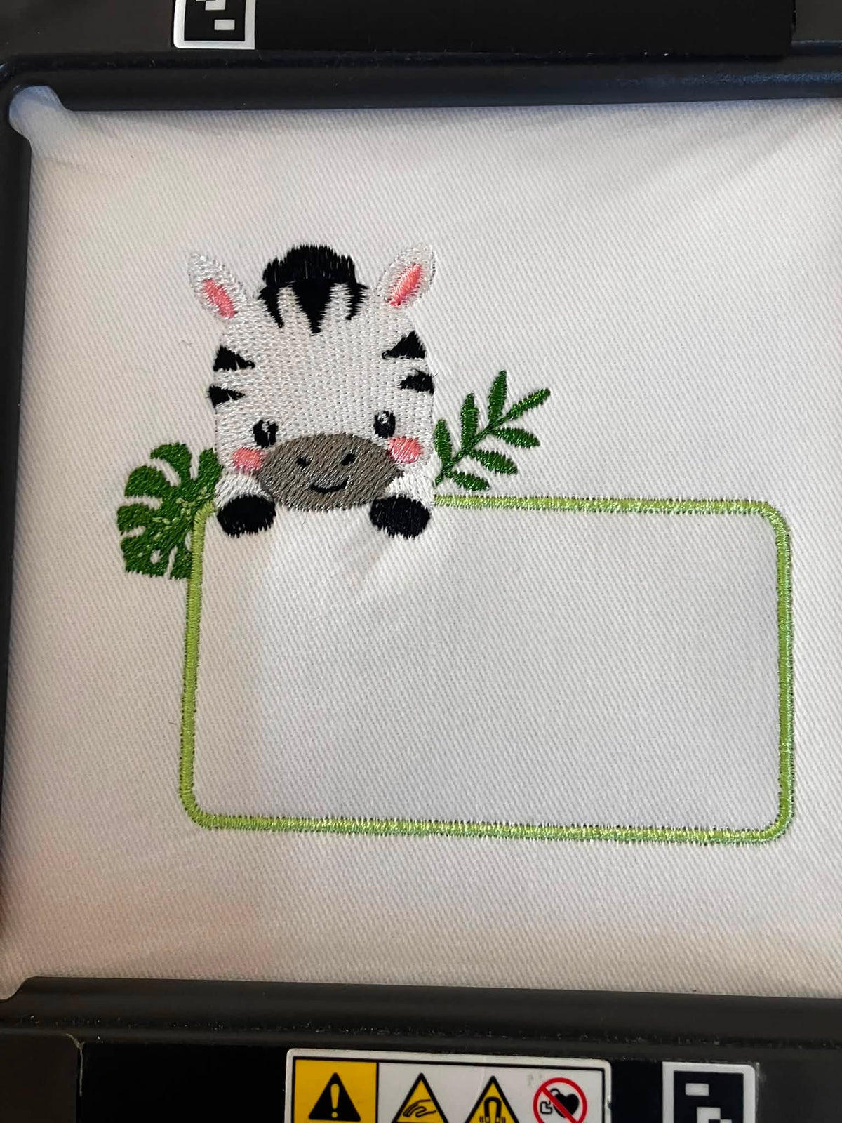 Motif de broderie Étiquette Zèbre personnalisable avec petit zèbre mignon, feuillages tropicaux et cadre pour ajouter un prénom ou un texte au format 10x10