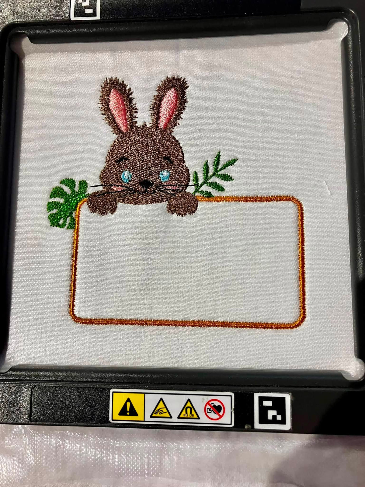Motif de broderie Étiquette Lapin personnalisable avec petit lapin, feuillages et cadre pour ajouter un prénom ou un texte au format 10x10