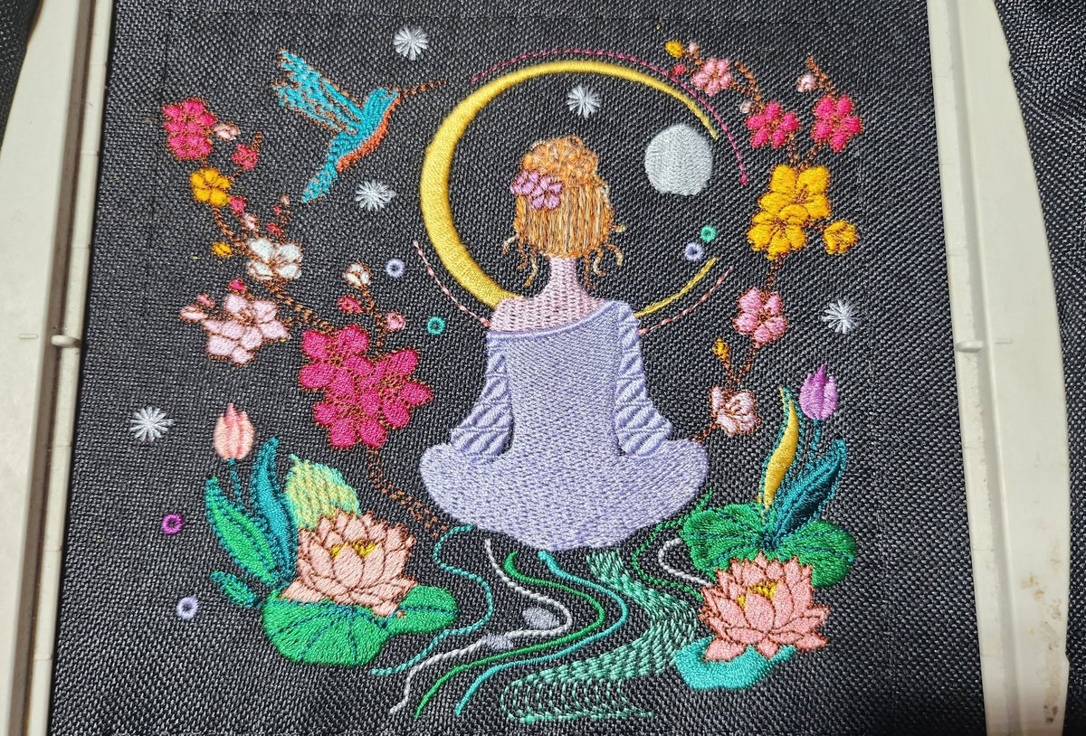 Méditation au Jardin des Songes – femme méditant entourée de fleurs, lotus, lune et colibri – motif de broderie machine