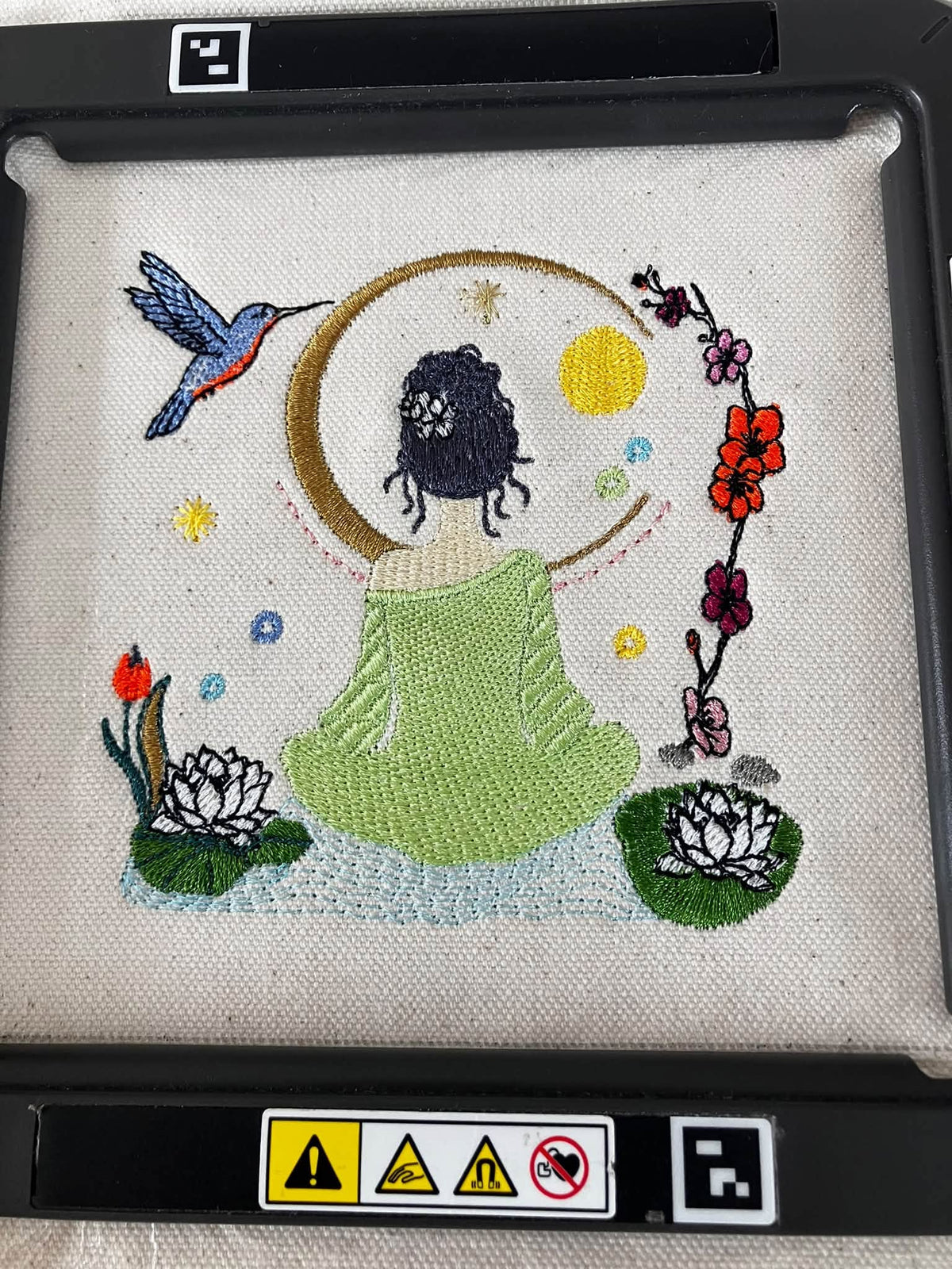 Méditation au Jardin des Songes – femme méditant entourée de fleurs, lotus, lune et colibri – motif de broderie machine