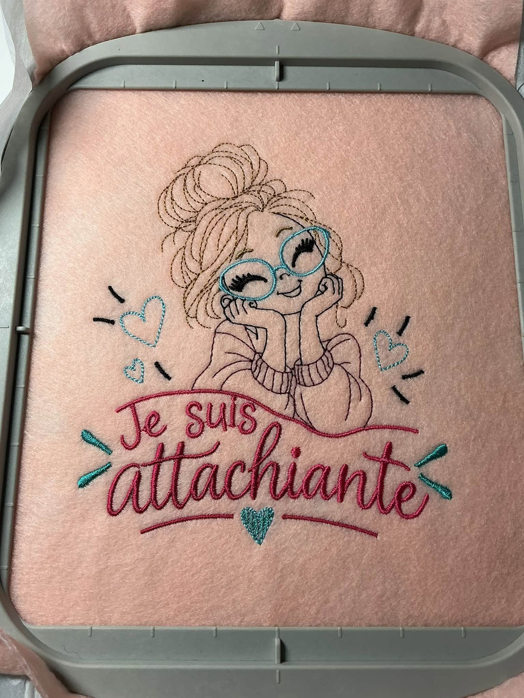 Je suis Attachiante – femme avec chignon, grandes lunettes rouges et petits cœurs – motif de broderie machine humour