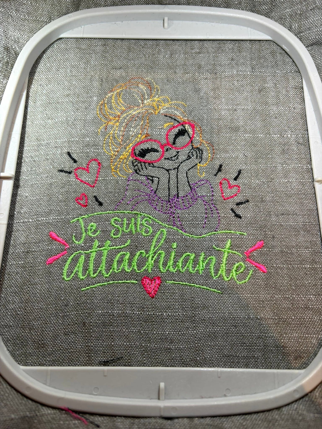 Je suis Attachiante – femme avec chignon, grandes lunettes rouges et petits cœurs – motif de broderie machine humour