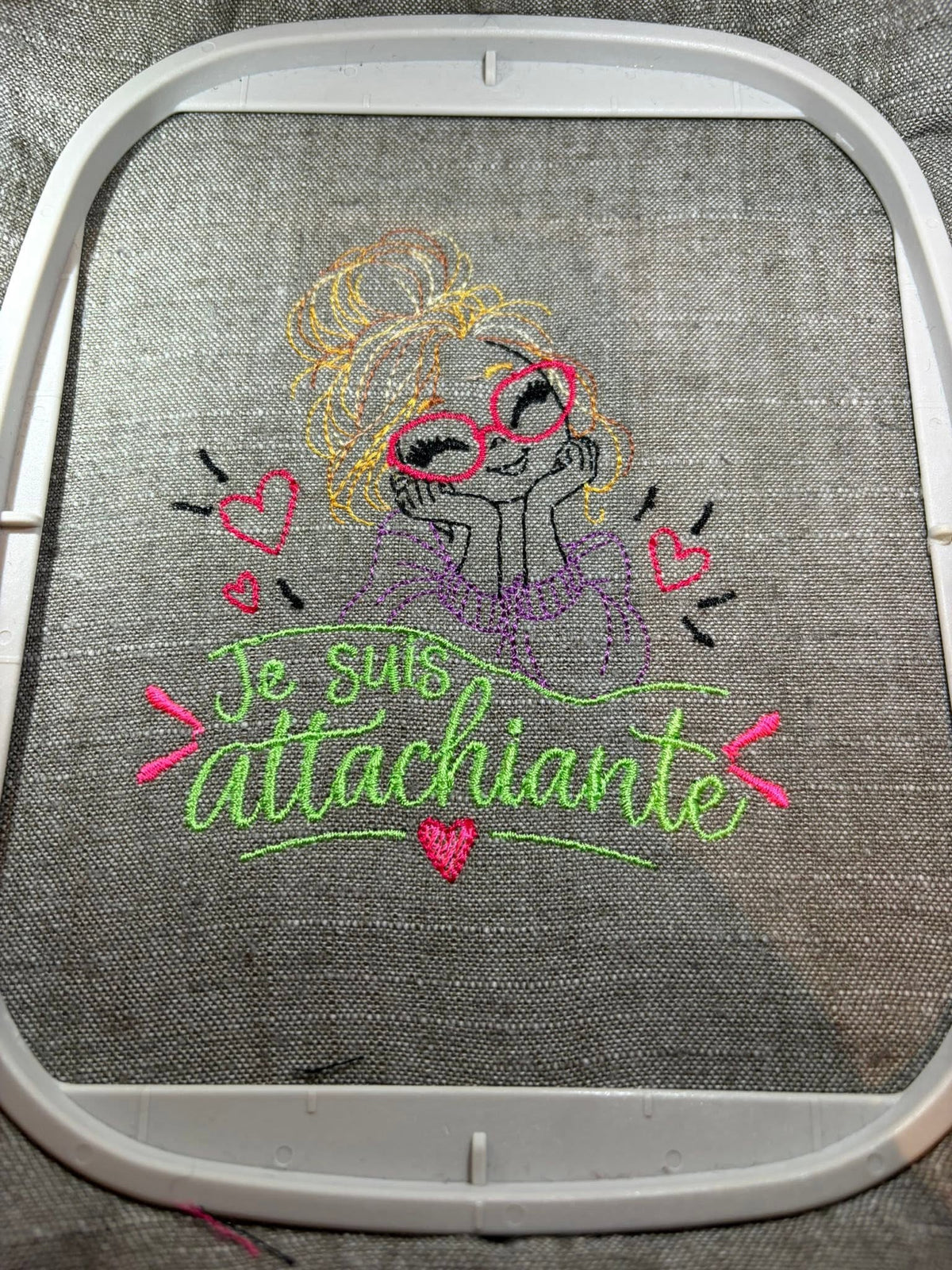 Je suis Attachiante – femme avec chignon, grandes lunettes rouges et petits cœurs – motif de broderie machine humour