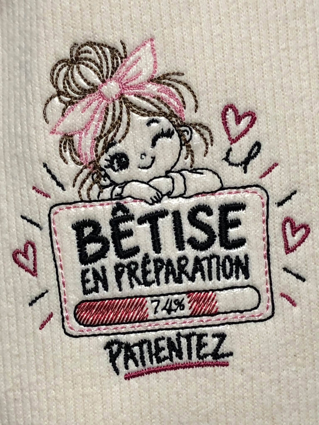Bêtise en Préparation – petite fille malicieuse avec grand nœud rose et barre de chargement à 74 % – motif broderie machine 10x10