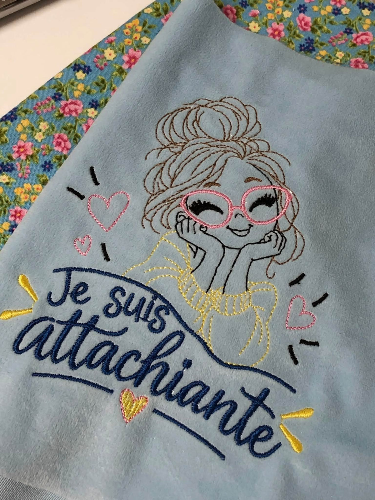 Je suis Attachiante – femme avec chignon, grandes lunettes rouges et petits cœurs – motif de broderie machine humour