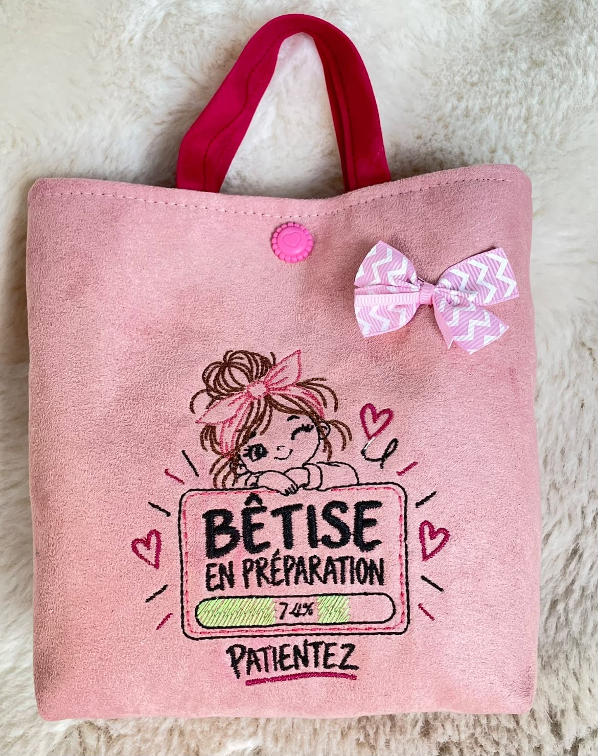 Bêtise en Préparation – petite fille malicieuse avec grand nœud rose et barre de chargement à 74 % – motif broderie machine 10x10