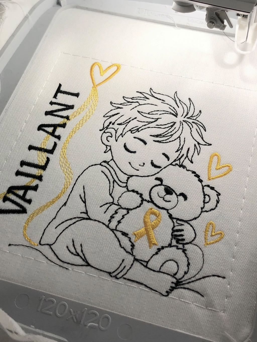 Le Petit Vaillant, petit garçon serrant un ourson avec ruban doré, cœurs et message VAILLANT – motif broderie Septembre en Or