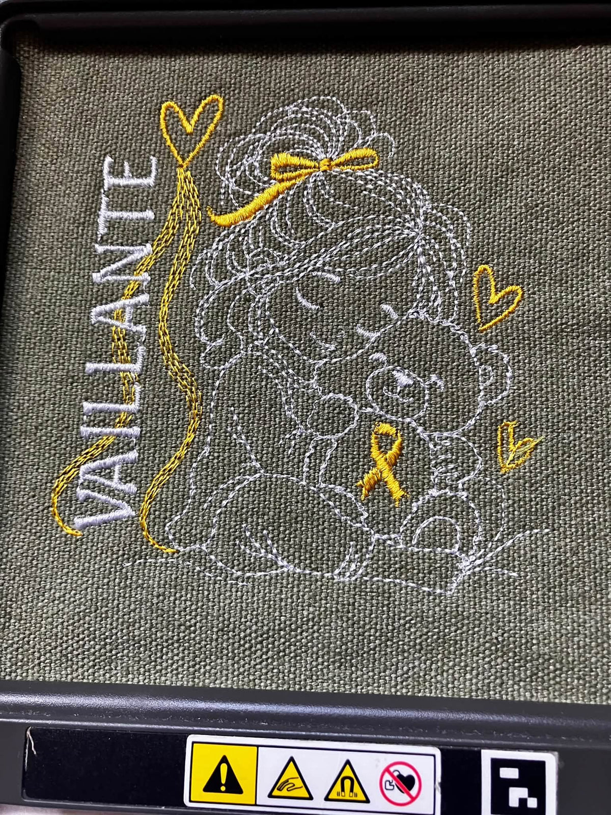 La Petite Vaillante, petite fille serrant un ourson avec ruban doré, cœurs et message VAILLANTE – motif broderie Septembre en Or