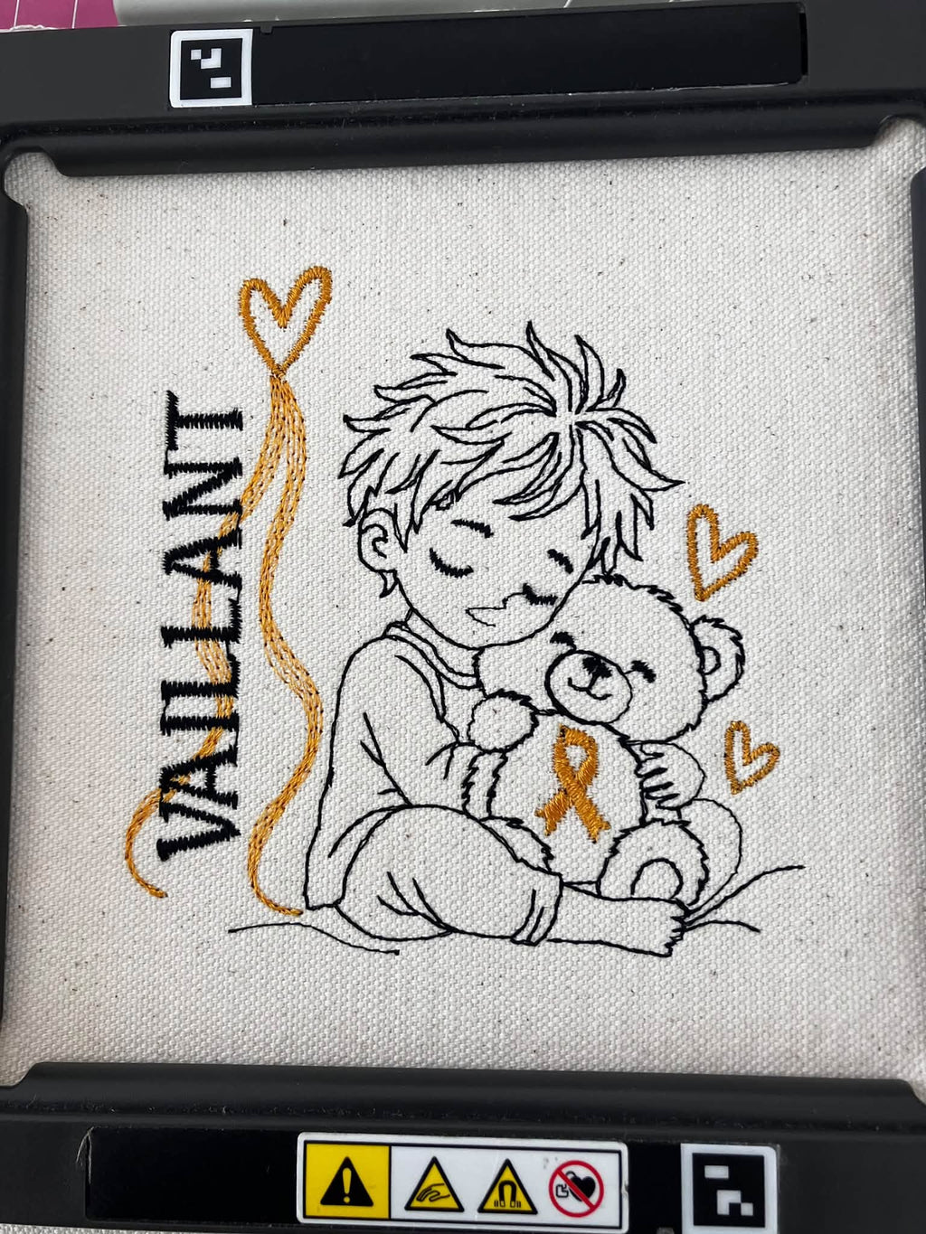Le Petit Vaillant, petit garçon serrant un ourson avec ruban doré, cœurs et message VAILLANT – motif broderie Septembre en Or
