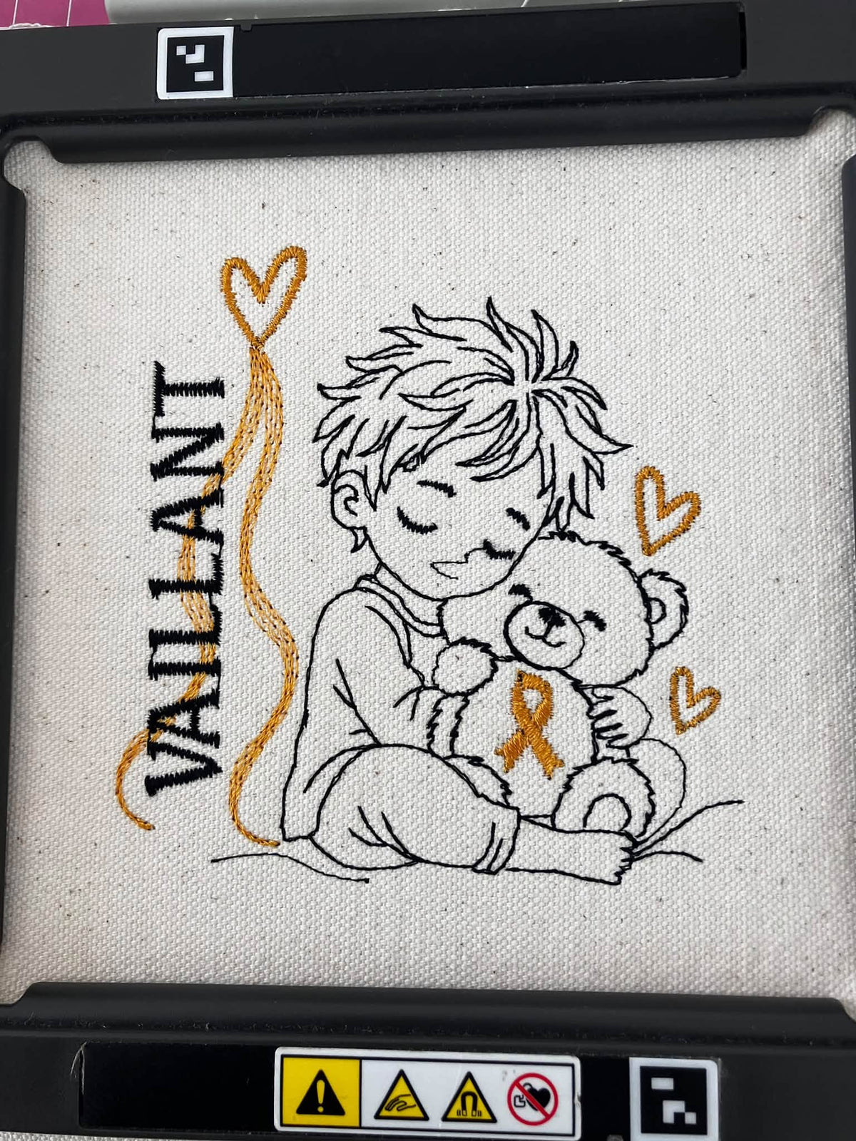 Le Petit Vaillant, petit garçon serrant un ourson avec ruban doré, cœurs et message VAILLANT – motif broderie Septembre en Or