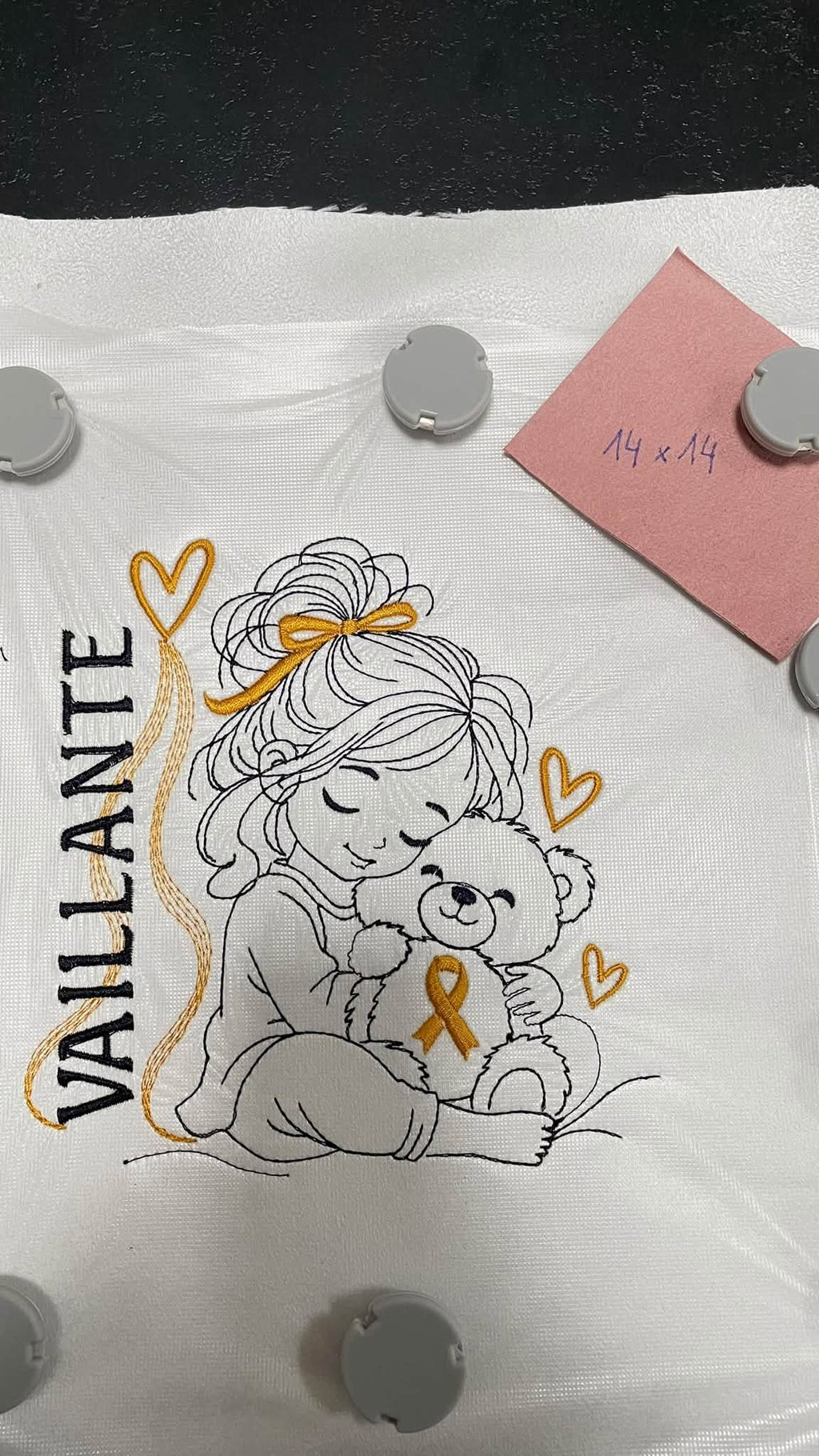 La Petite Vaillante, petite fille serrant un ourson avec ruban doré, cœurs et message VAILLANTE – motif broderie Septembre en Or