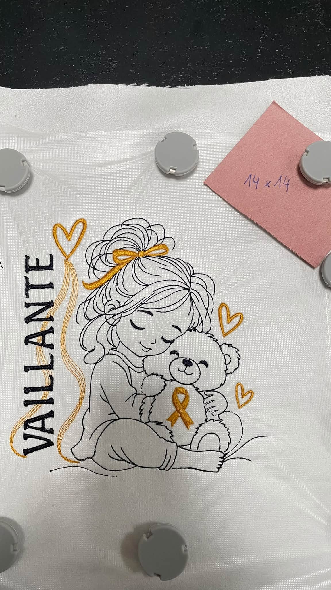 La Petite Vaillante, petite fille serrant un ourson avec ruban doré, cœurs et message VAILLANTE – motif broderie Septembre en Or