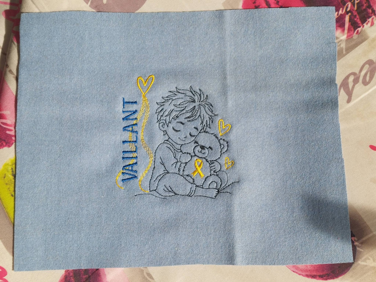 Le Petit Vaillant, petit garçon serrant un ourson avec ruban doré, cœurs et message VAILLANT – motif broderie Septembre en Or