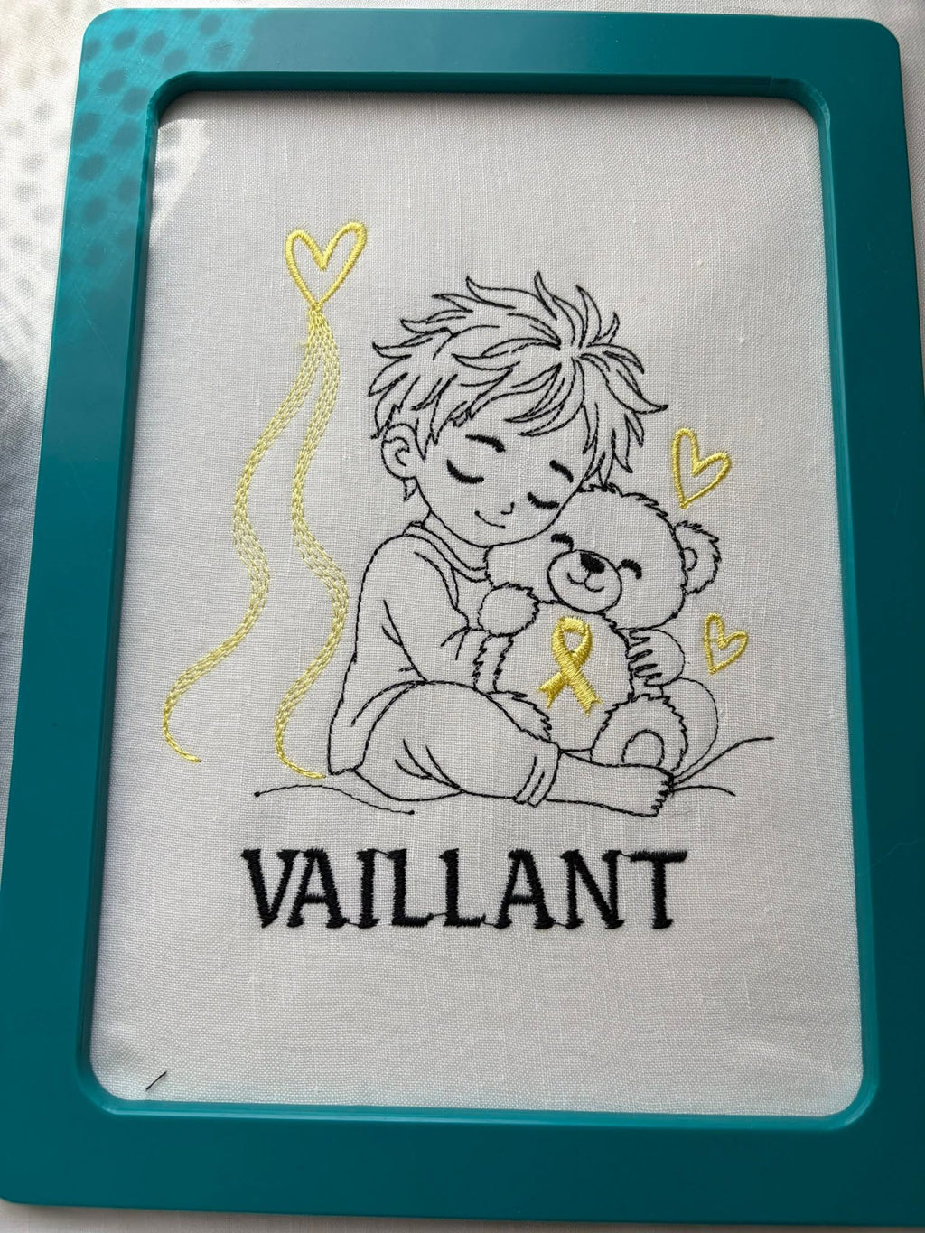 Le Petit Vaillant, petit garçon serrant un ourson avec ruban doré, cœurs et message VAILLANT – motif broderie Septembre en Or