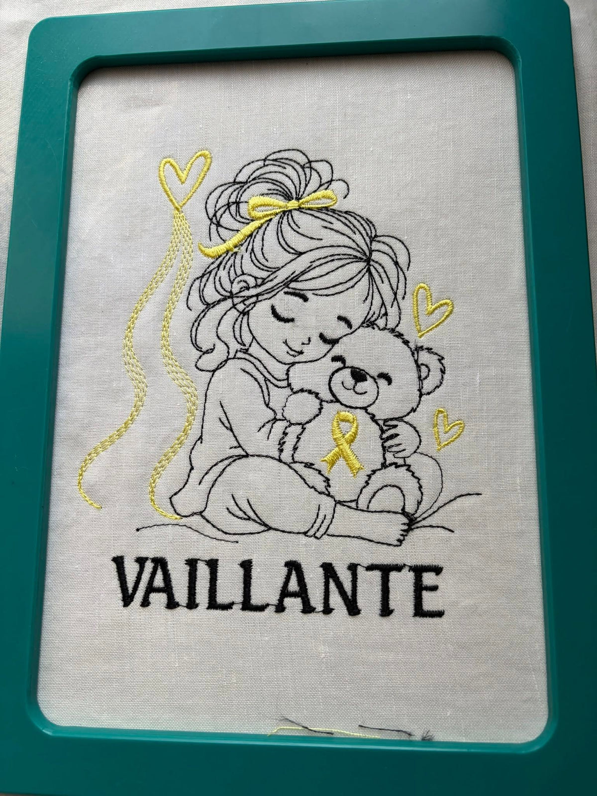 La Petite Vaillante, petite fille serrant un ourson avec ruban doré, cœurs et message VAILLANTE – motif broderie Septembre en Or