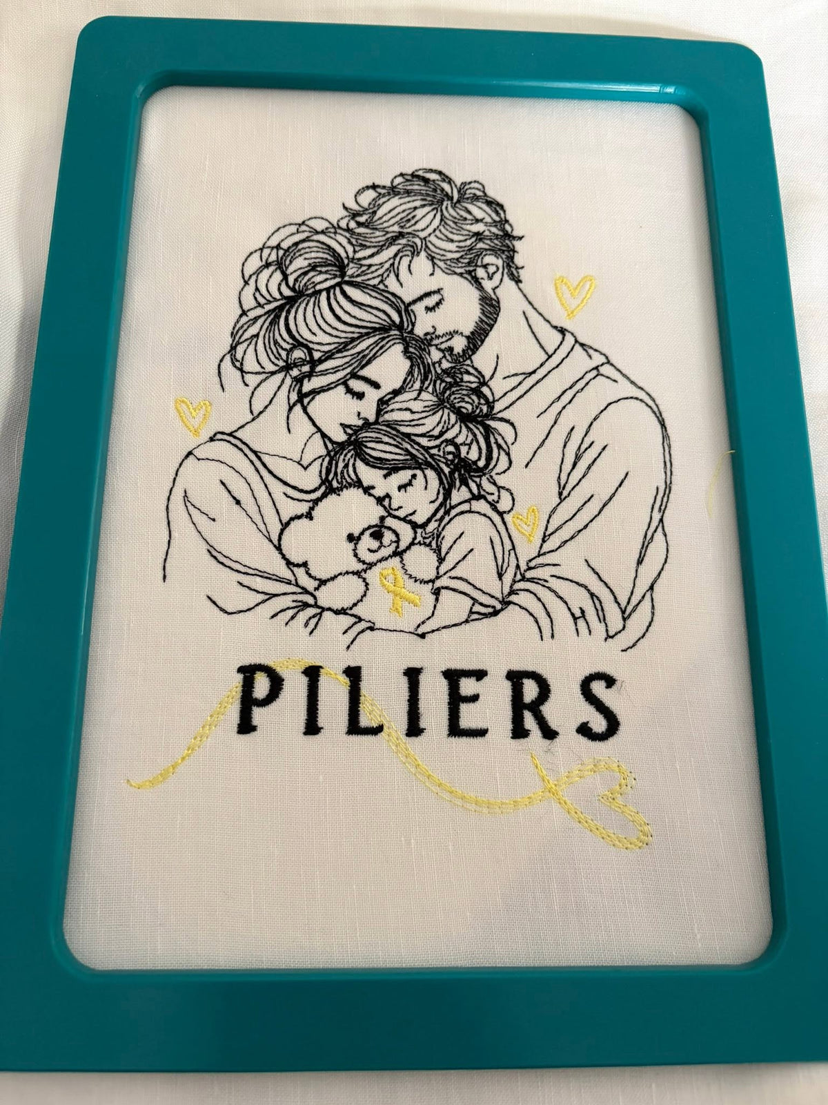Ensemble Les Piliers – famille unie avec papa, maman et petite fille serrant un ourson au ruban doré – motif broderie Septembre en Or