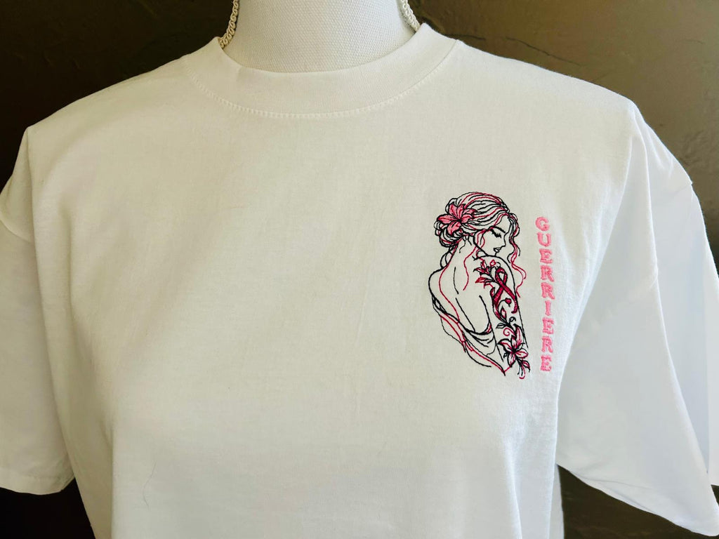 T-shirt blanc coupe classique brodé avec le motif Guerrière Octobre Rose, création originale AK Broderie avec silhouette féminine, tatouage floral et ruban rose.