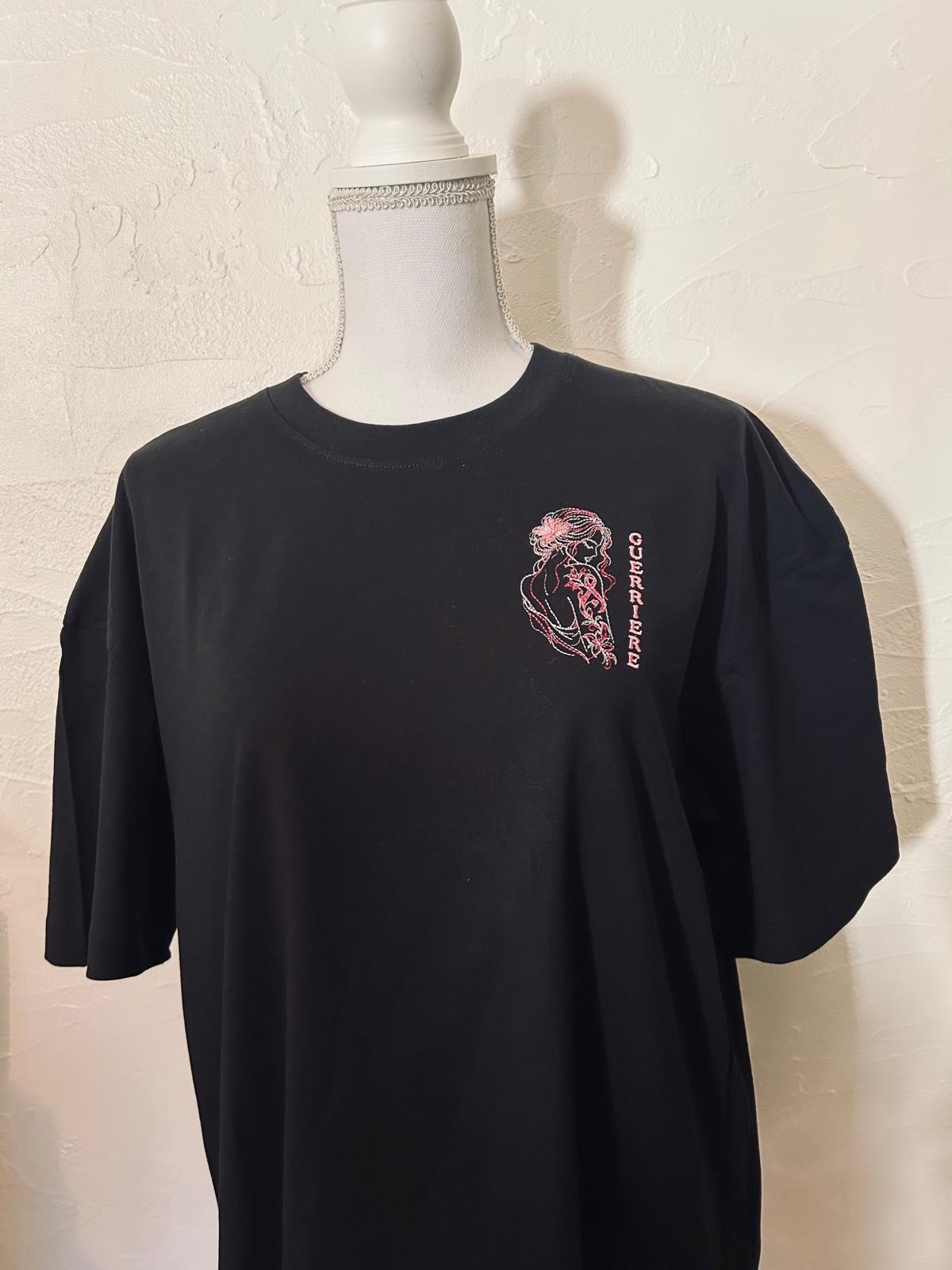 T-shirt noir oversize brodé avec le motif Guerrière Octobre Rose, création originale AK Broderie représentant une silhouette féminine ornée d’un tatouage floral et du ruban rose.