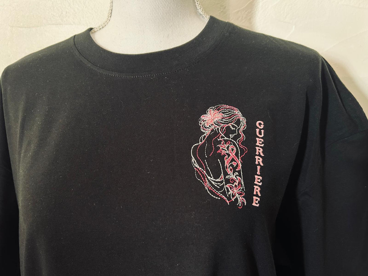 T-shirt noir oversize brodé avec le motif Guerrière Octobre Rose, création originale AK Broderie représentant une silhouette féminine ornée d’un tatouage floral et du ruban rose.
